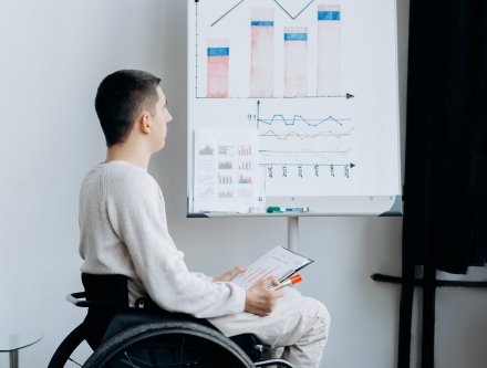 man in wheelchair looking at board
