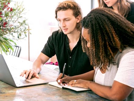 one person taking notes while other person is looking at computer